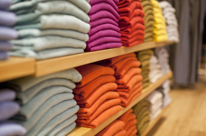 Colorful display of sweaters on shelf in store Retail cloths supply chain